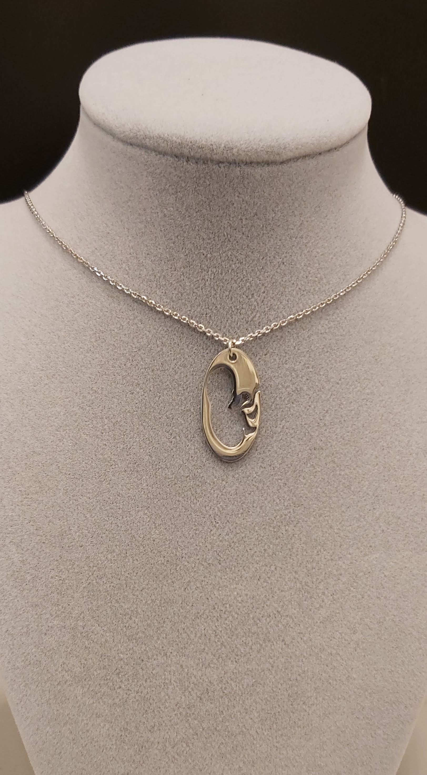 Collar de plata con diseño de feto en el útero. 
